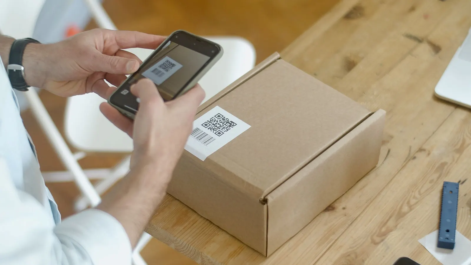 A person scanning the QR code on a cardboard shipping box with a smartphone