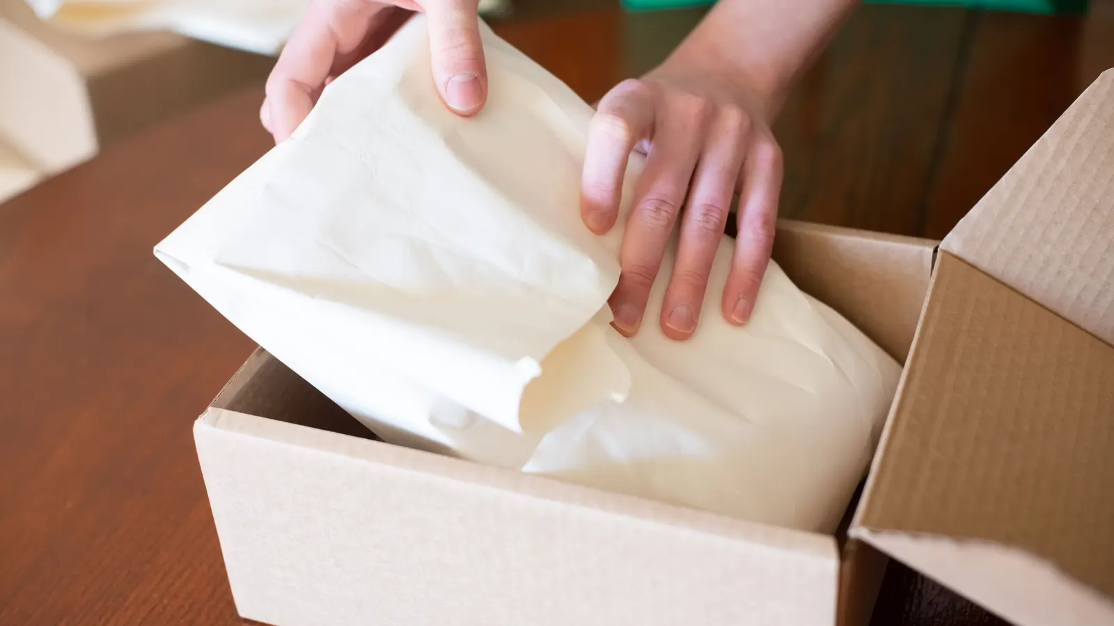 Kleiner Onlinehändler packt Versandkartons — Sinnbild für die PPWR-Belastung im Kleinversand