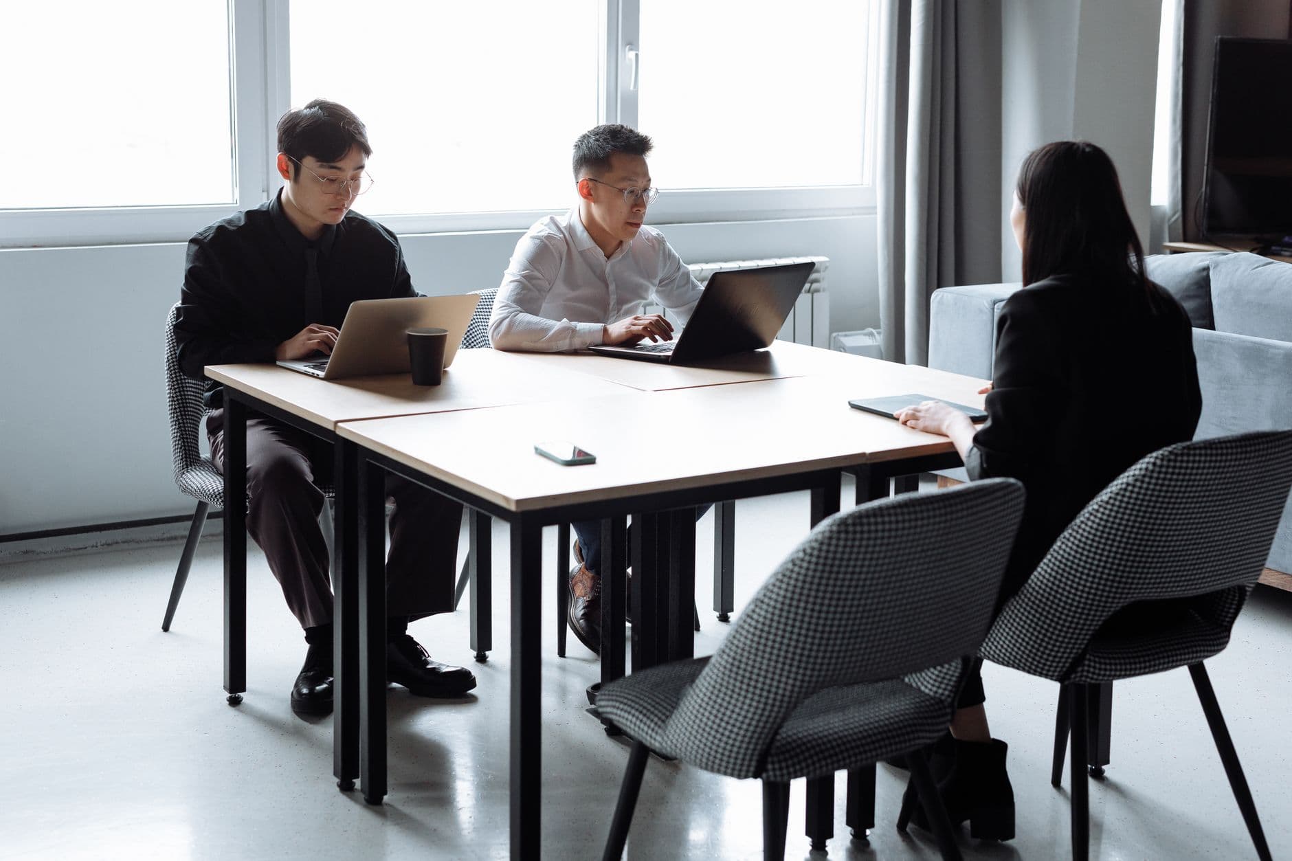 Three colleagues working intently on laptops in a bright office
