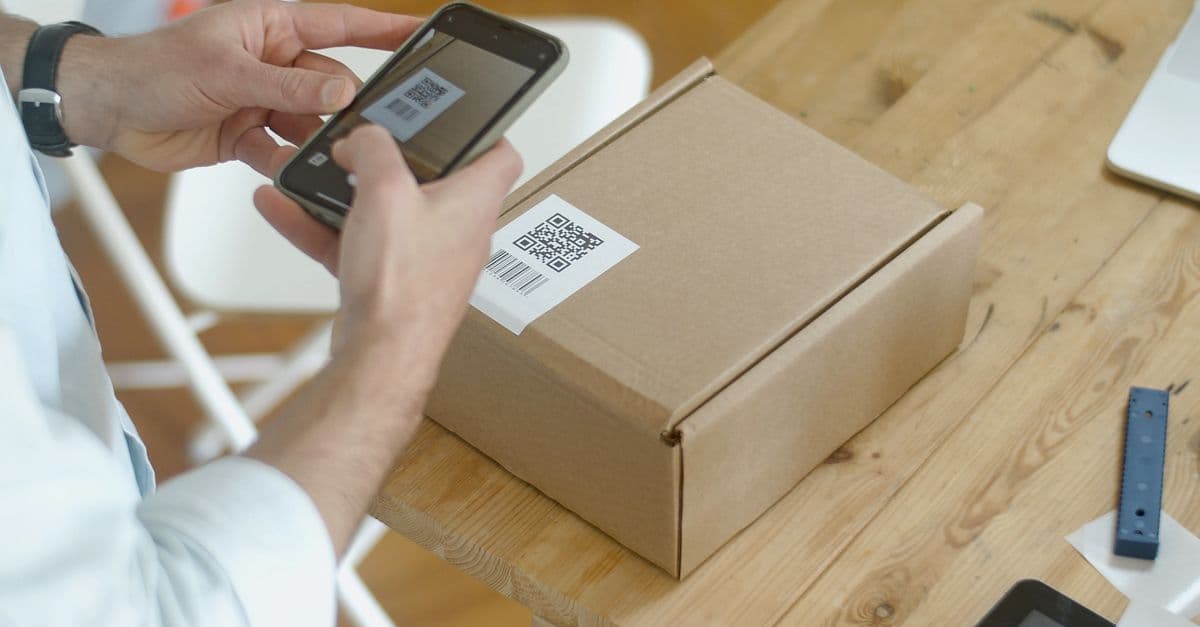 Smartphone scannt QR-Code auf einem Versandkarton