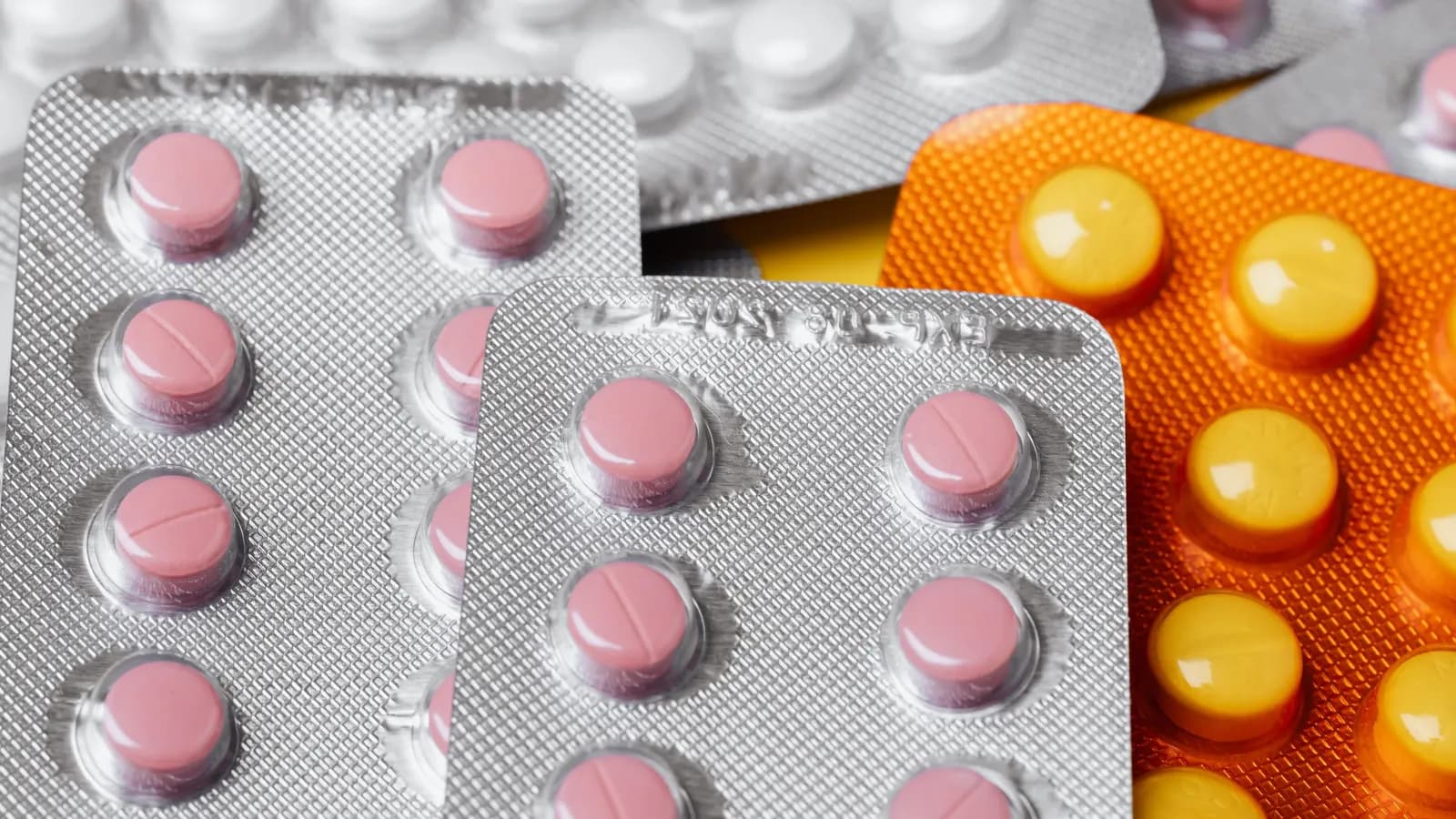 Blisterpackungen mit rosa und gelben Tabletten in Nahaufnahme — Symbolbild für Primärverpackungen von Arzneimitteln