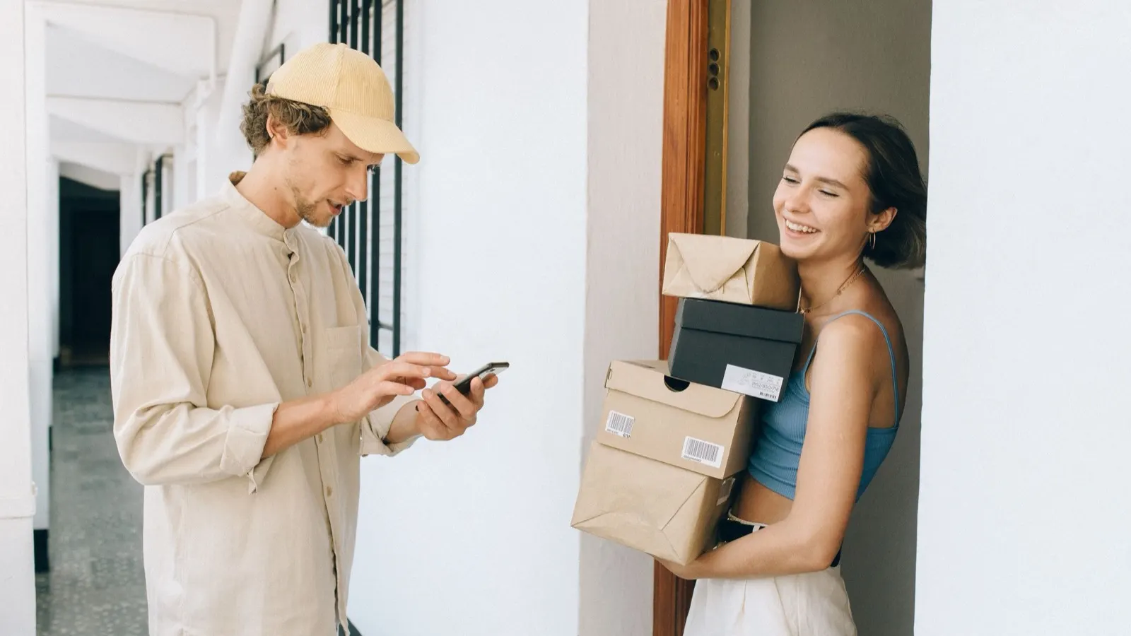 Paketübergabe an der Wohnungstür mit Smartphone in der Hand