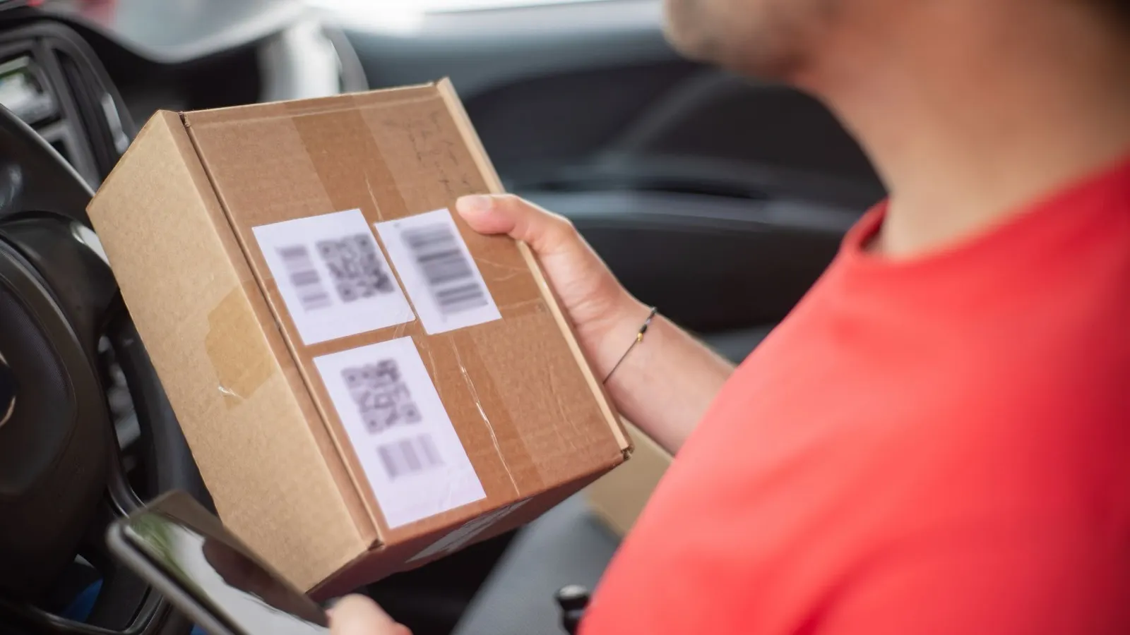Paket mit QR-Codes in der Hand — digitaler Datenträger auf der Verpackung